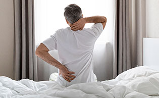 A man getting out of bed suffering from back pain