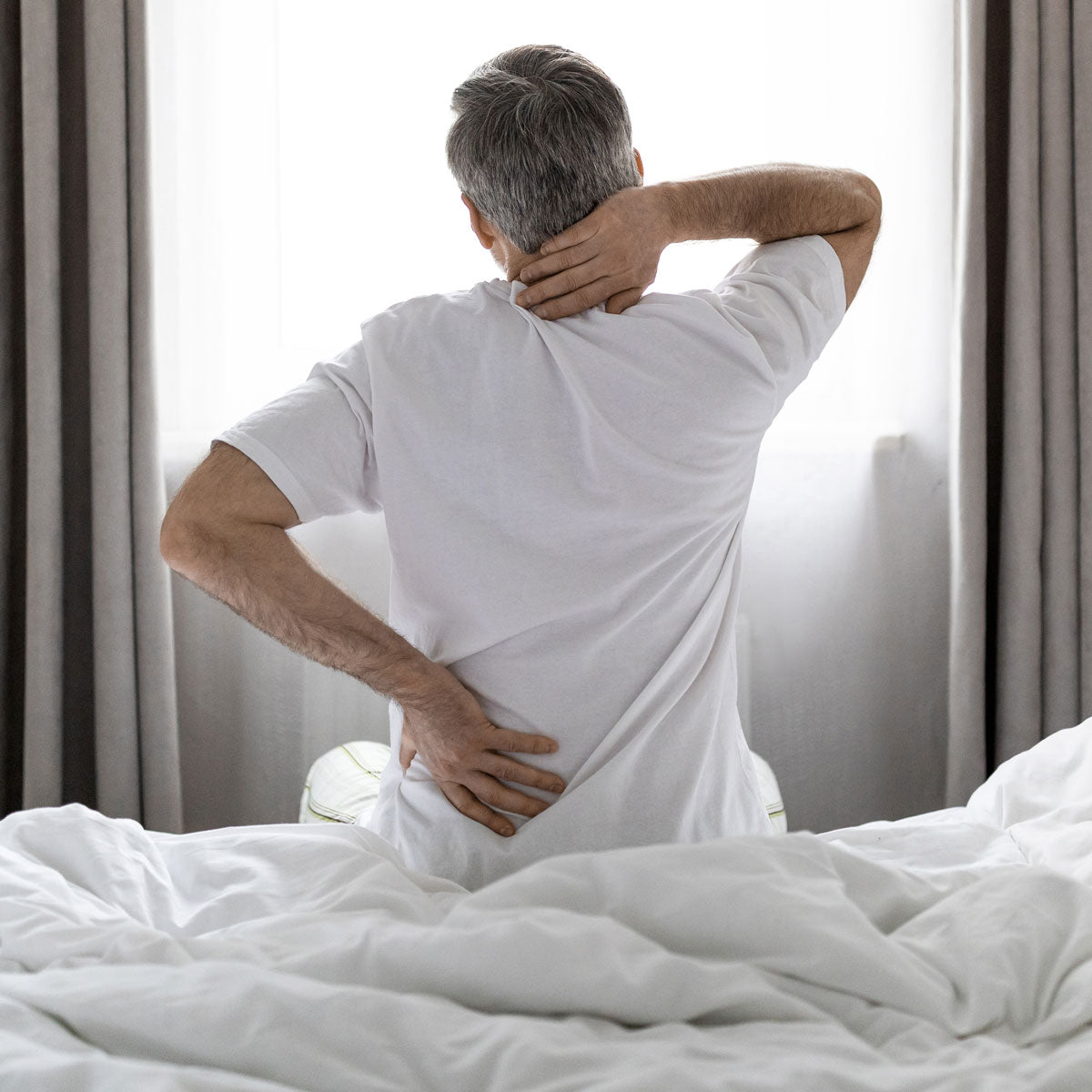 A man getting out of bed with back pain